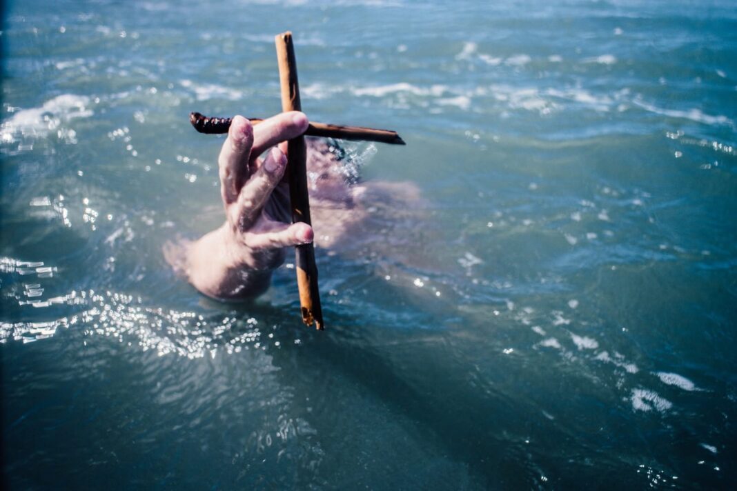 релігійна свобода людини під водою тримає коричневий дерев'яний хрест над водою в денний час